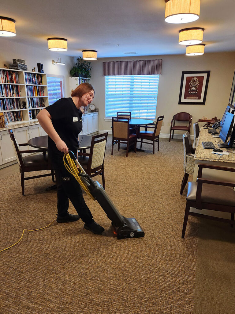 A woman cleaning the room with a vacuum cleaner, making the space spotless and dust-free.