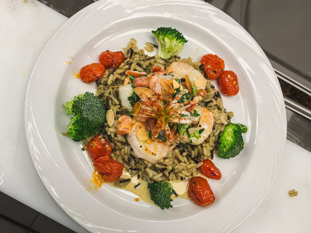 Appetizing meal with shrimp, rice, tomatoes, and broccoli served on a plate.