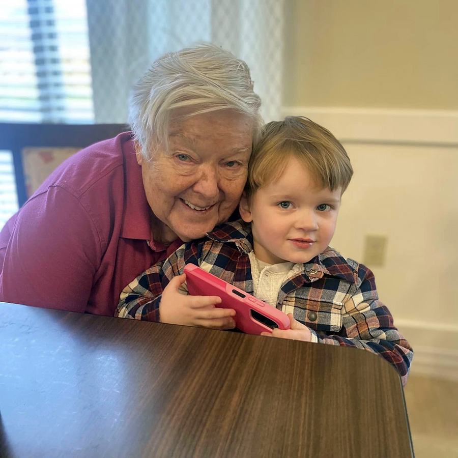 An intergenerational bond captured in a heartwarming photo: a smiling older woman and a young boy sitting at a table.