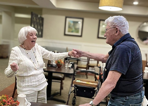 A senior man and woman dance, hands linked, at The Wildwood Senior Living.