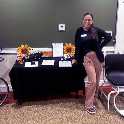 A team member smiles next to a table full of themed resources for a wellness event.
