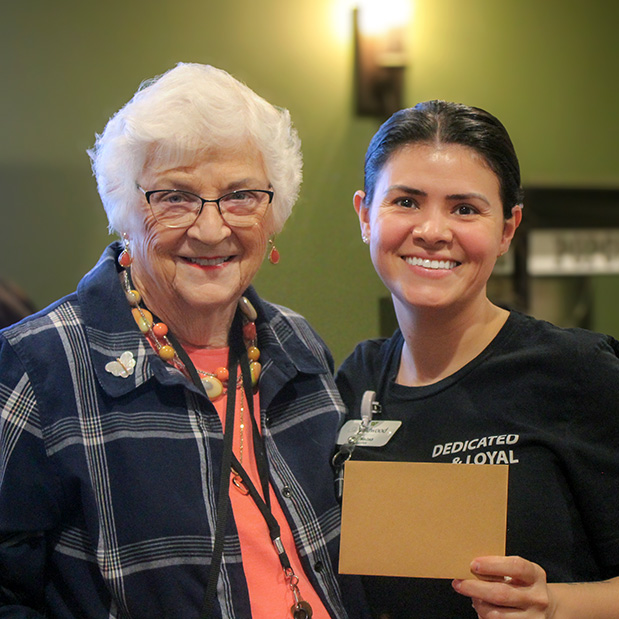 A senior woman and team member smile together at The Wildwood Senior Living.